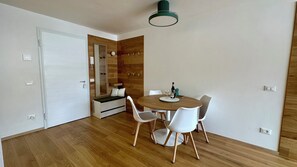 A modern dining area with a wooden table, white chairs, and a mirror on the wall. - AlpenGlow SkiLodge (Corteno Golgi)