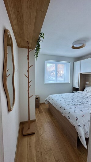 A bedroom with a bed, a wooden coat rack, a window, and a ceiling light fixture. - AlpenGlow SkiLodge (Corteno Golgi)