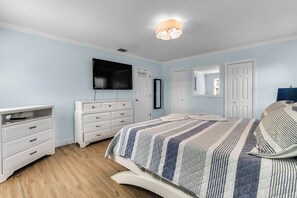 Ein Schlafzimmer mit Bett, Schminktisch, Fernseher und Deckenleuchte.