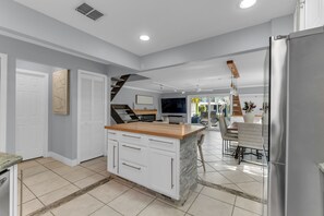 A modern kitchen with a central island, white cabinetry, and a stainless steel refrigerator. - Family Friendly Waterfront Ft Lauderdale Retreat (Fort Lauderdale)