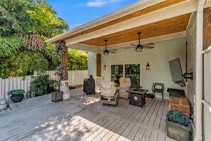Eine überdachte Terrasse im Freien mit Holzboden, Deckenventilatoren und Sitzmöbeln.