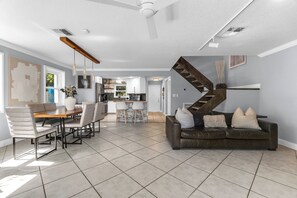 Ein modernes Wohnzimmer mit einer braunen Ledersofa, einem Essbereich mit Holztisch und -stühlen sowie einer Küche im Hintergrund.