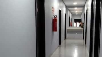 A long, narrow hallway with doors on both sides, a fire extinguisher mounted on the wall, and a clean, tiled floor.