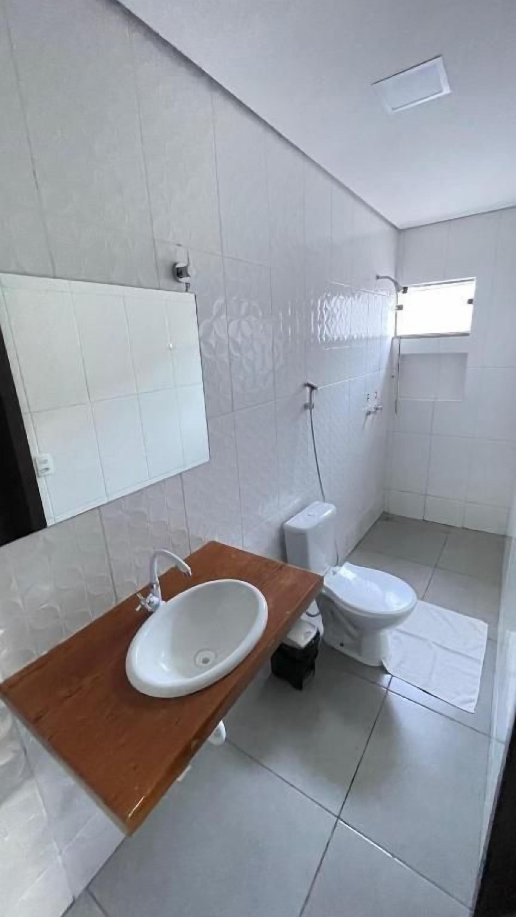 Ein Badezimmer mit einem Holzkosmetikschrank, einem Waschbecken, einer Toilette und einer Dusche.