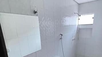 Ein Badezimmer mit einem Holzkosmetikschrank, einem Waschbecken, einer Toilette und einer Dusche.