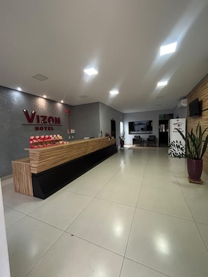 A hotel reception area with a reception desk, a wall-mounted sign, and a potted plant. - HOTEL VIZON II (Vilhena)