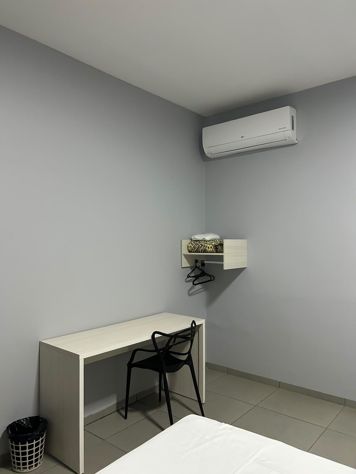 A small, neatly organized room with a desk, chair, and a hanging shelf with a patterned item.