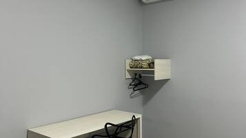 A small, neatly organized room with a desk, chair, and a hanging shelf with a patterned item.