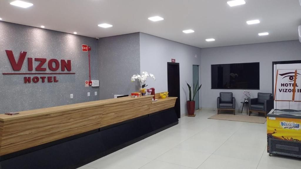 A hotel reception area with a reception desk, a plant, and a wall-mounted sign.