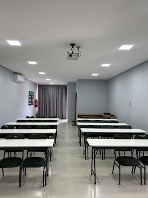A classroom with rows of desks and chairs, a projector, and a fire extinguisher on the wall. - HOTEL VIZON II (Vilhena)