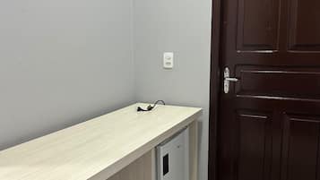 A room with a light-colored desk, a dark brown door, and a white electrical outlet.
