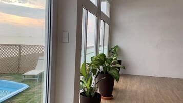 Un balcón amplio con vistas al mar, ventanas grandes y plantas en macetas.