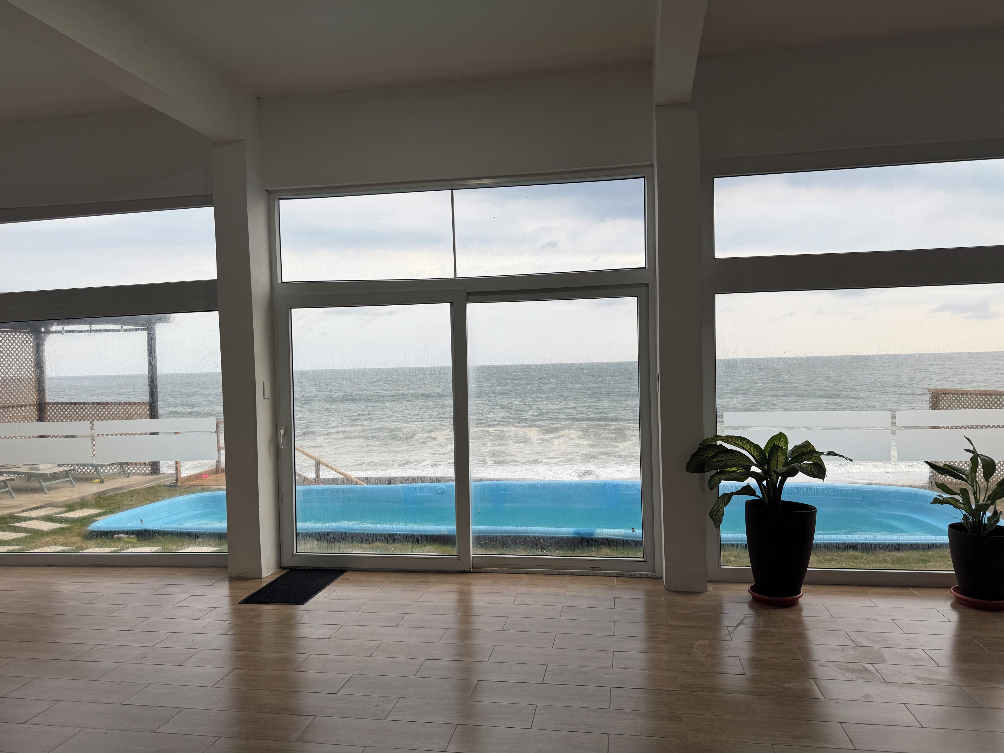 A room with large windows overlooking a beach and ocean.