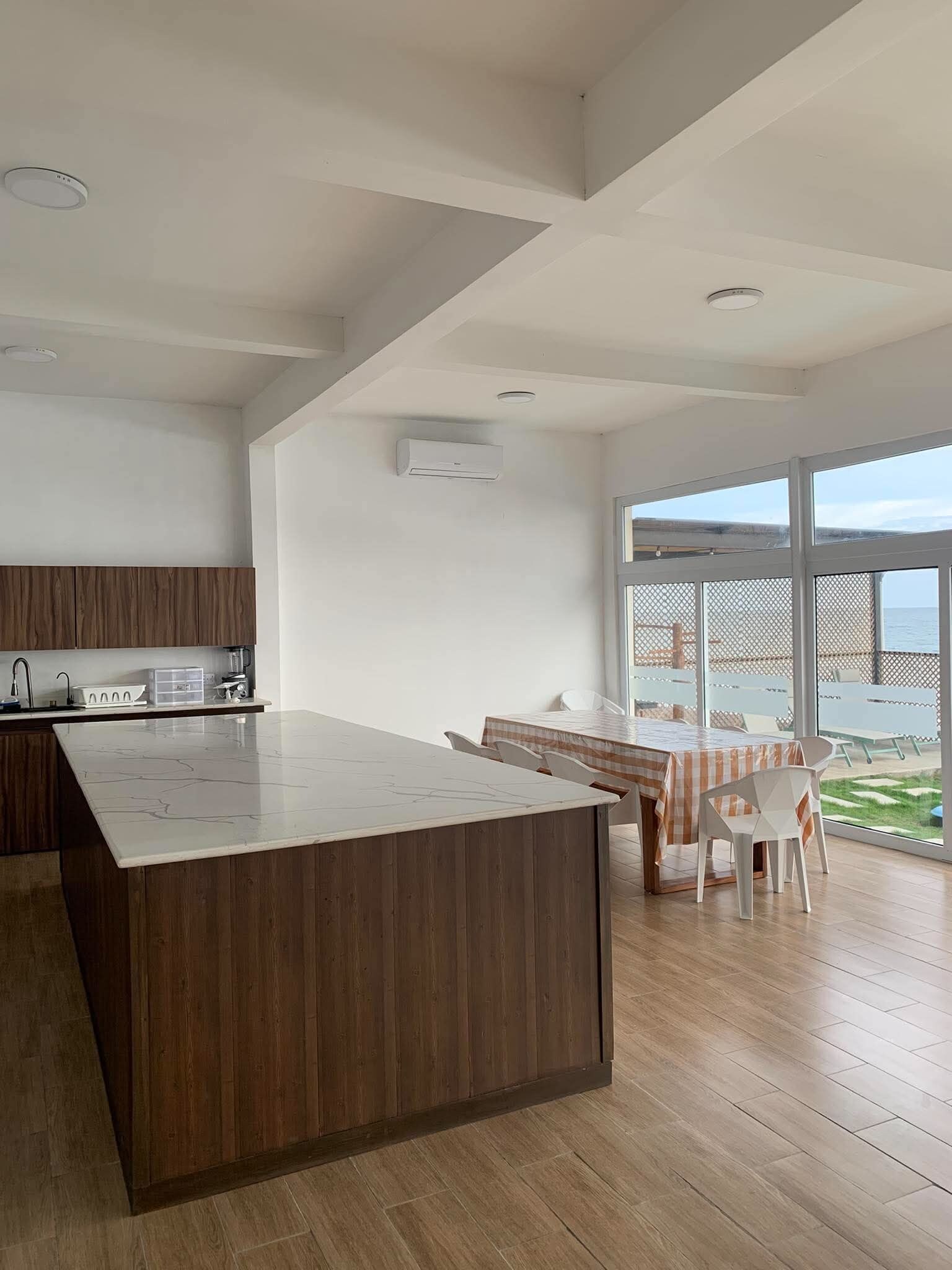 Una cocina moderna con una isla de madera, un comedor con vistas y un ventanal grande.
