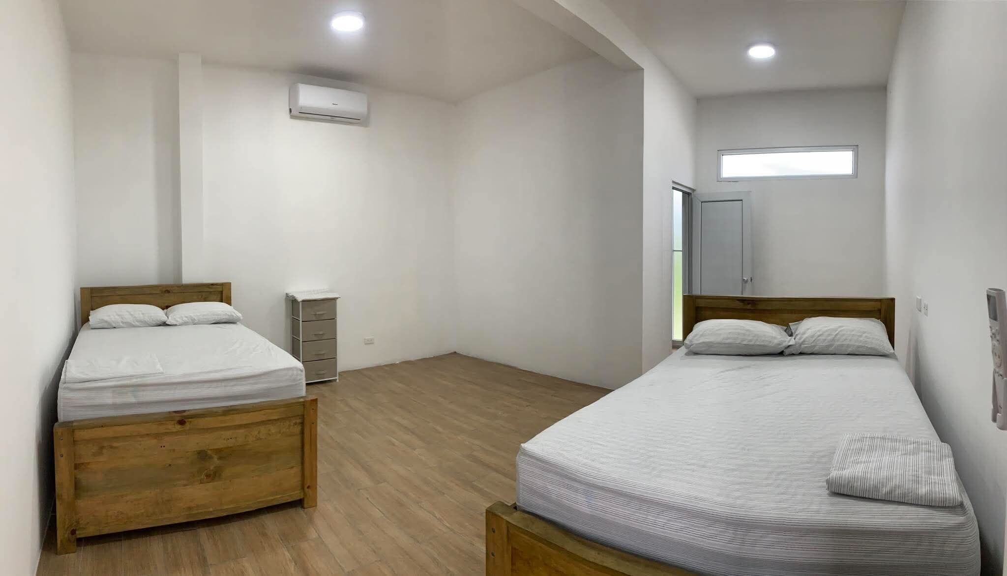 A room with two beds, a wardrobe, a heater, and a window.