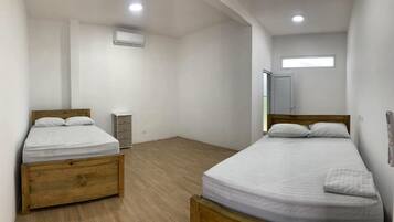 A room with two beds, a wardrobe, a heater, and a window.