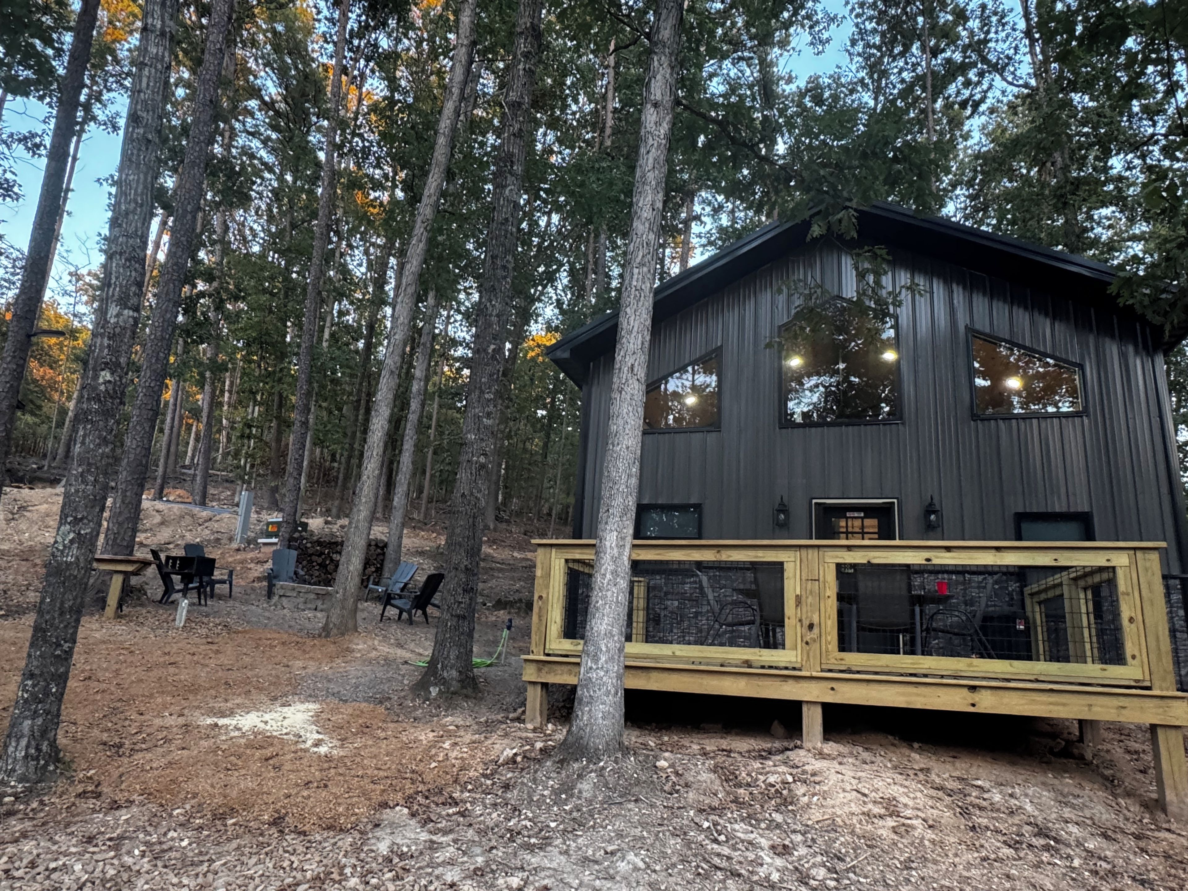 A cabin with a wooden deck, large windows, and a forested backdrop.
