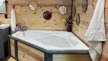 A wooden interior with a hot tub, wooden cabinets, and a mirror.