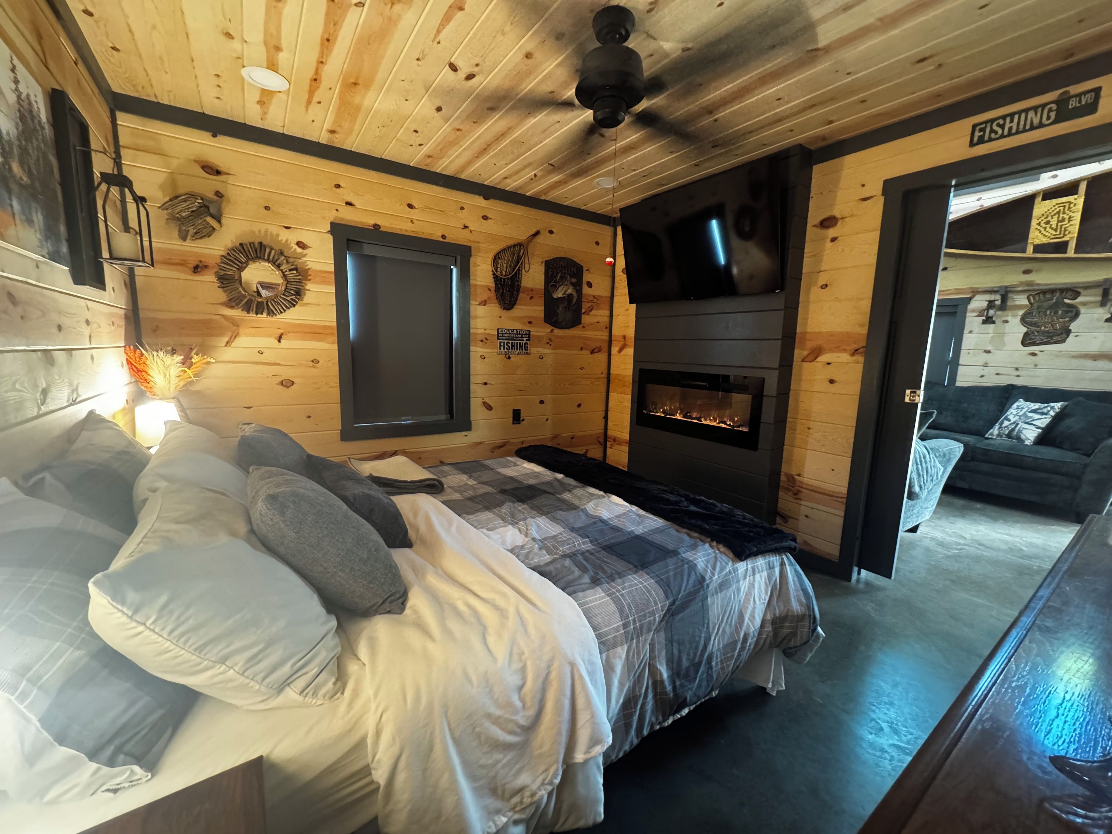 Une chambre confortable dans un chalet, avec un lit, une cheminée et un téléviseur fixé au mur.