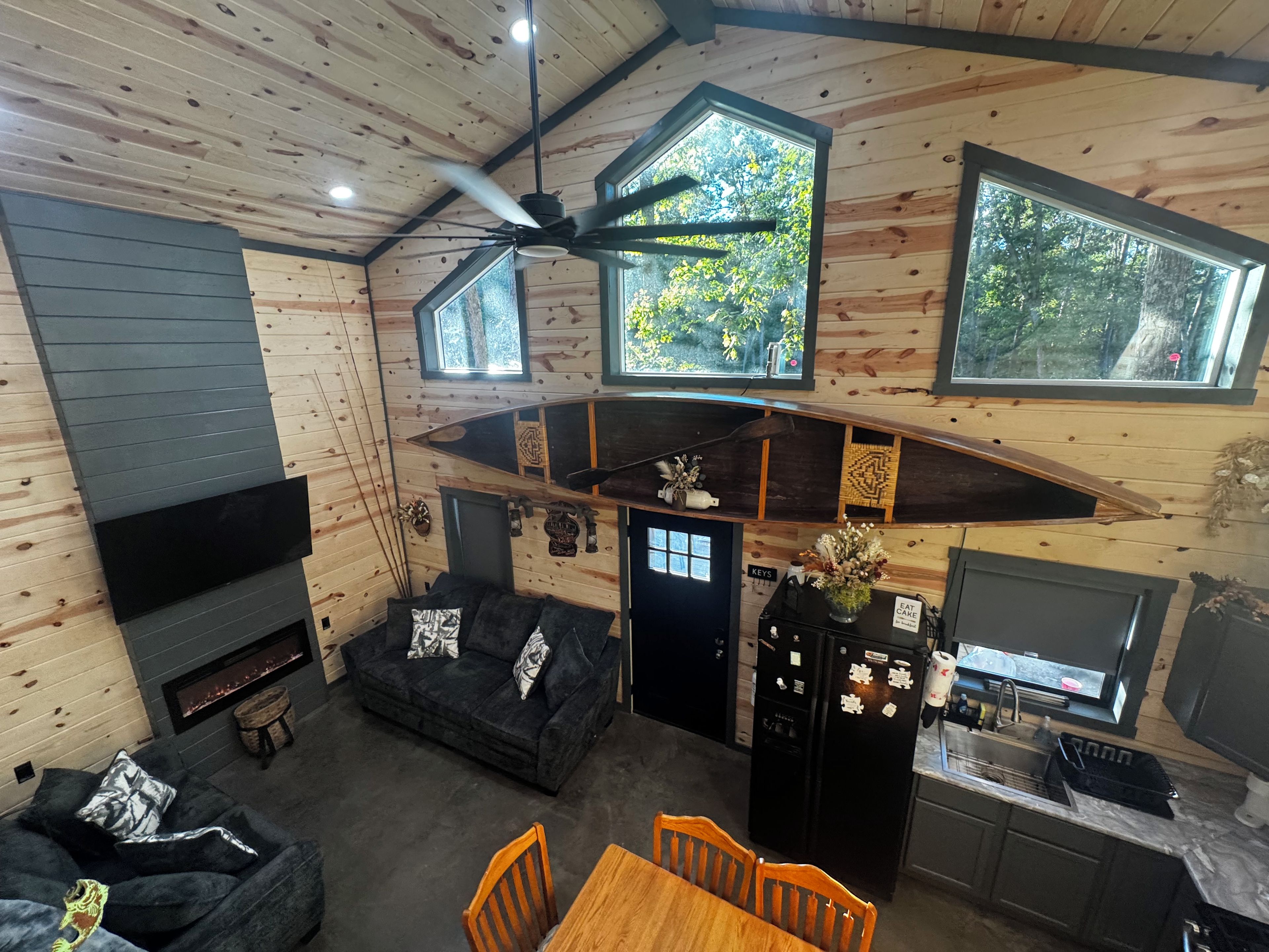 L’intérieur d’une cabane comprend une cheminée, un canapé, une table à manger et un coin cuisine.