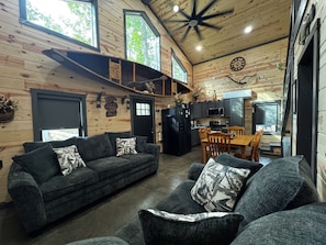 A cozy cabin interior with a sofa, dining table, and kitchen area.
