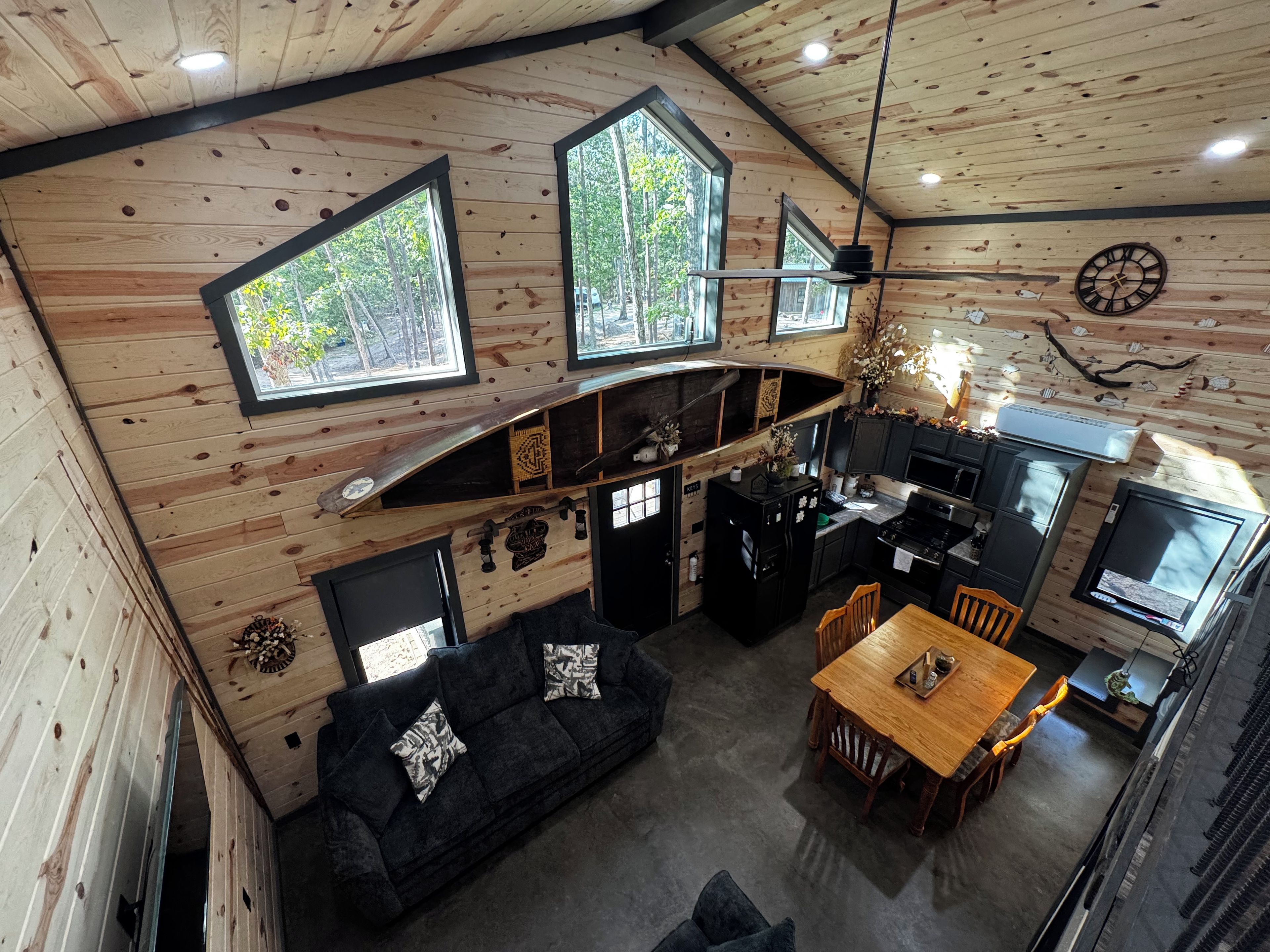 A cabin interior with a dining area, kitchen, and a sofa with decorative pillows.