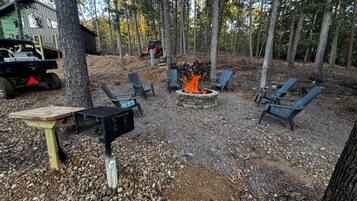 Un espace extérieur aménagé avec des chaises Adirondack, un foyer et un barbecue.