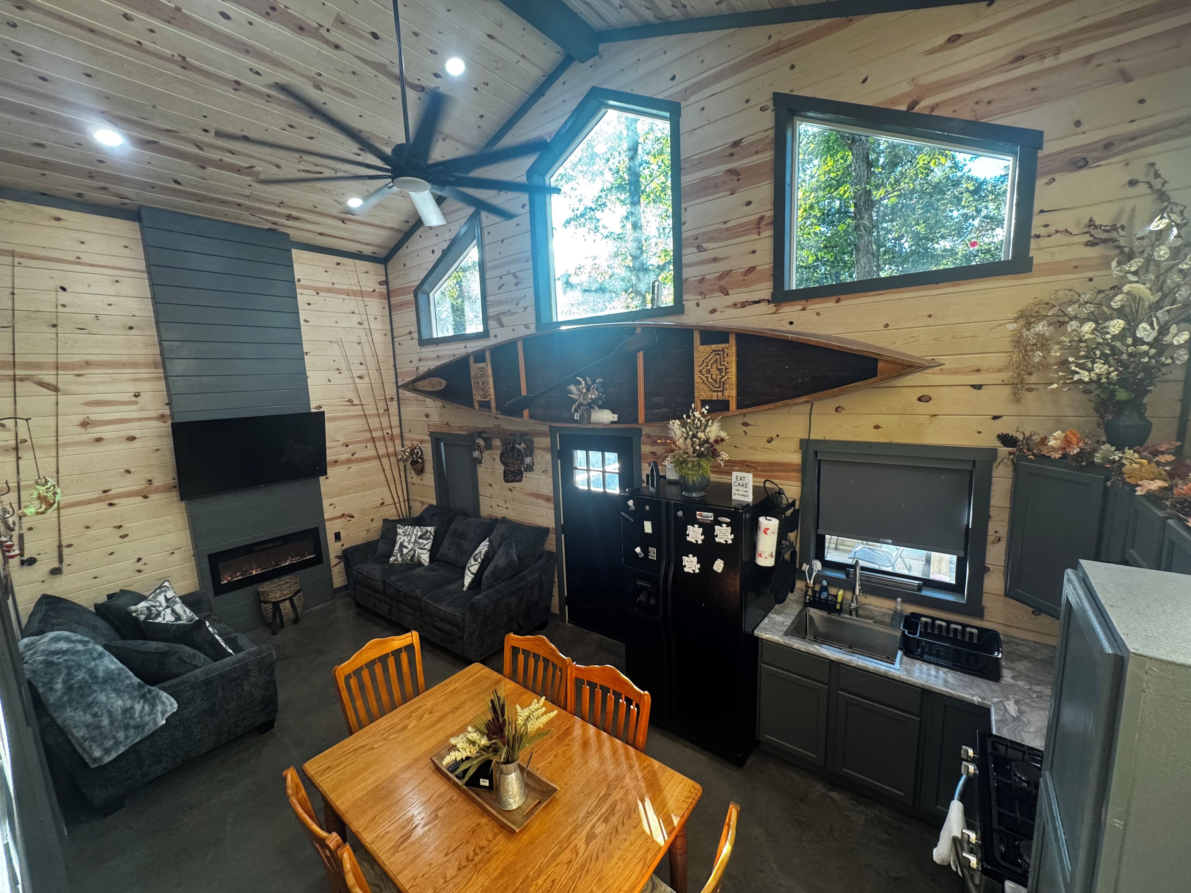 A cabin interior with a dining area, kitchen, and seating space.