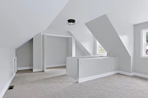 Ein Zimmer mit schrägem Dach, Heizkörper und Fenster.
