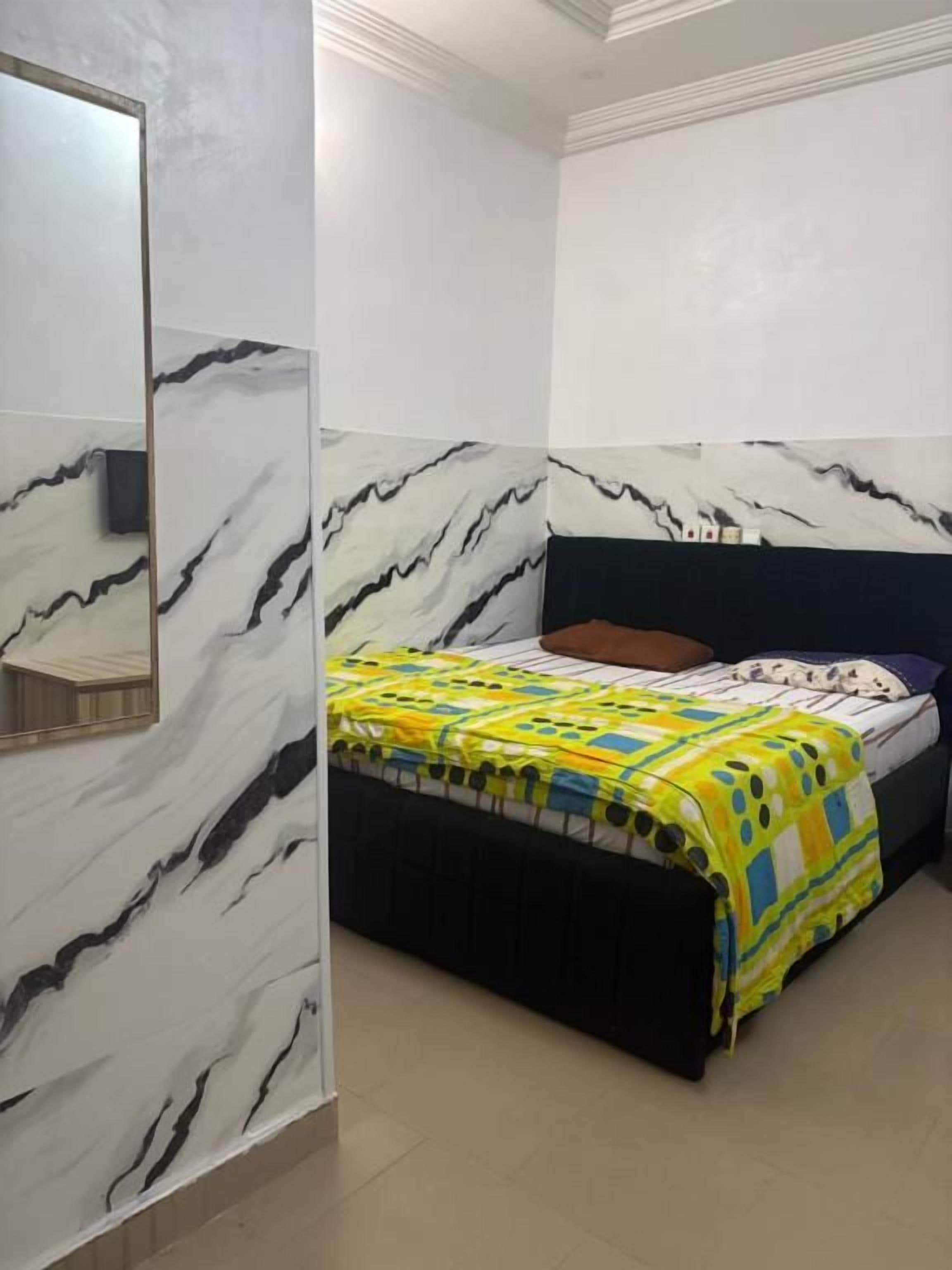 Un dormitorio con una cama, una mesita de noche y un espejo.
