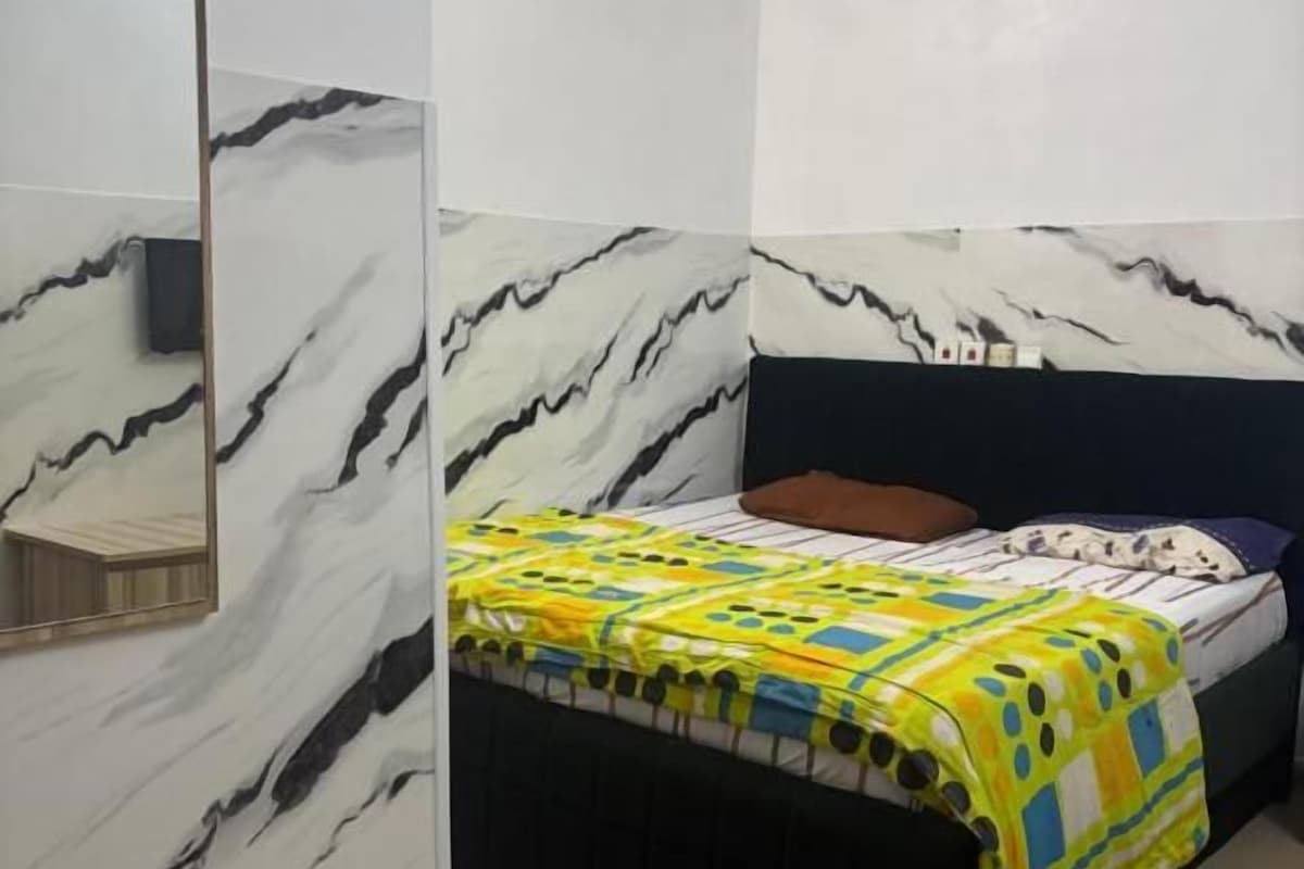 Quarto com cama, mesa de cabeceira e espelho.