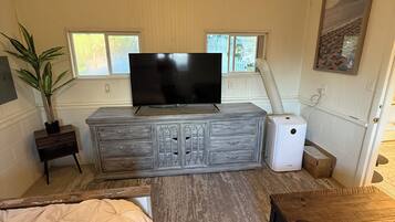 A bedroom with a bed, a dresser, a television, and a window.
