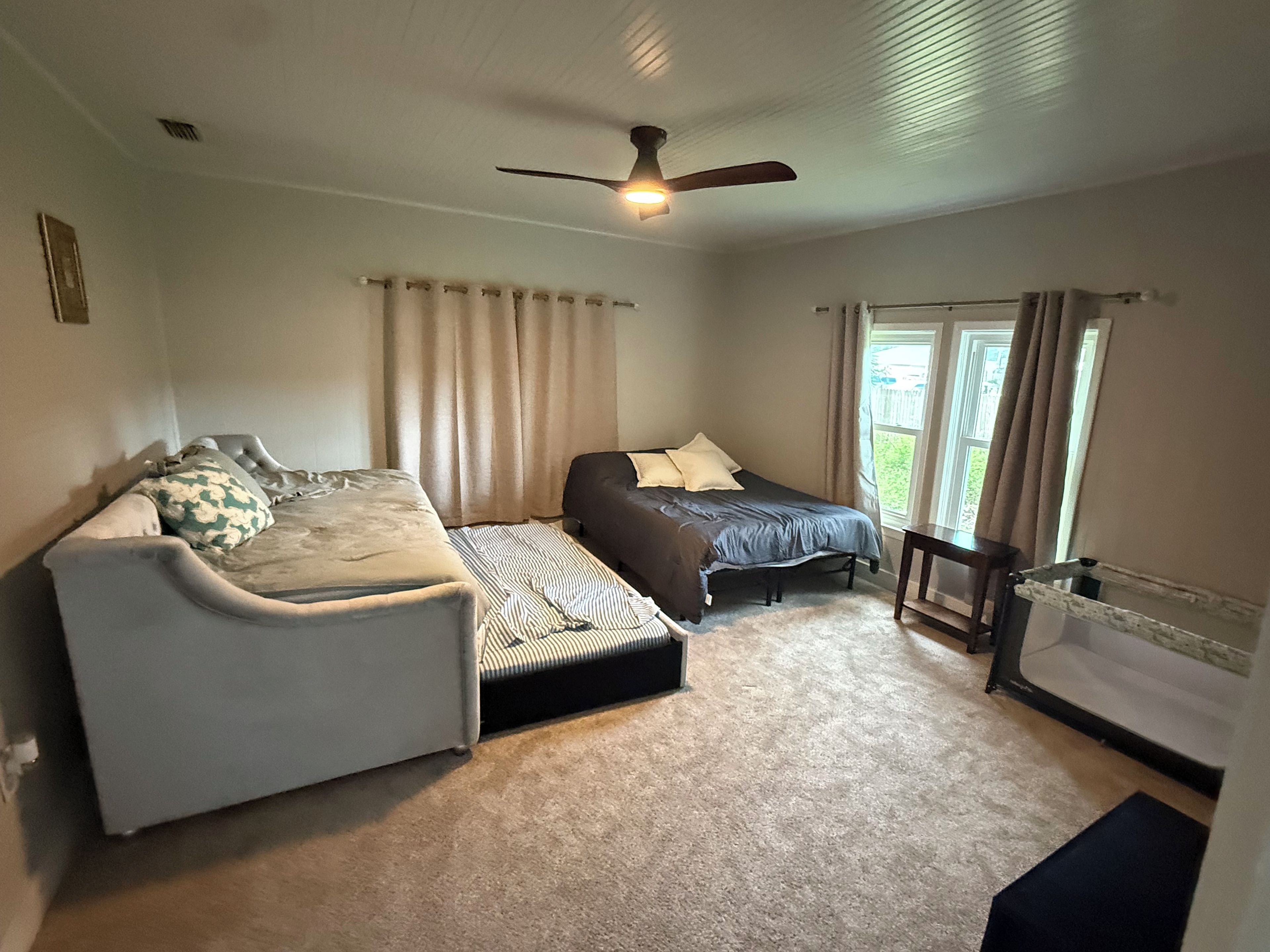 Une chambre à coucher avec un lit, un canapé, un ventilateur de plafond et une fenêtre.