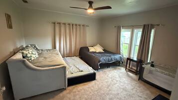 Une chambre à coucher avec un lit, un canapé, un ventilateur de plafond et une fenêtre.