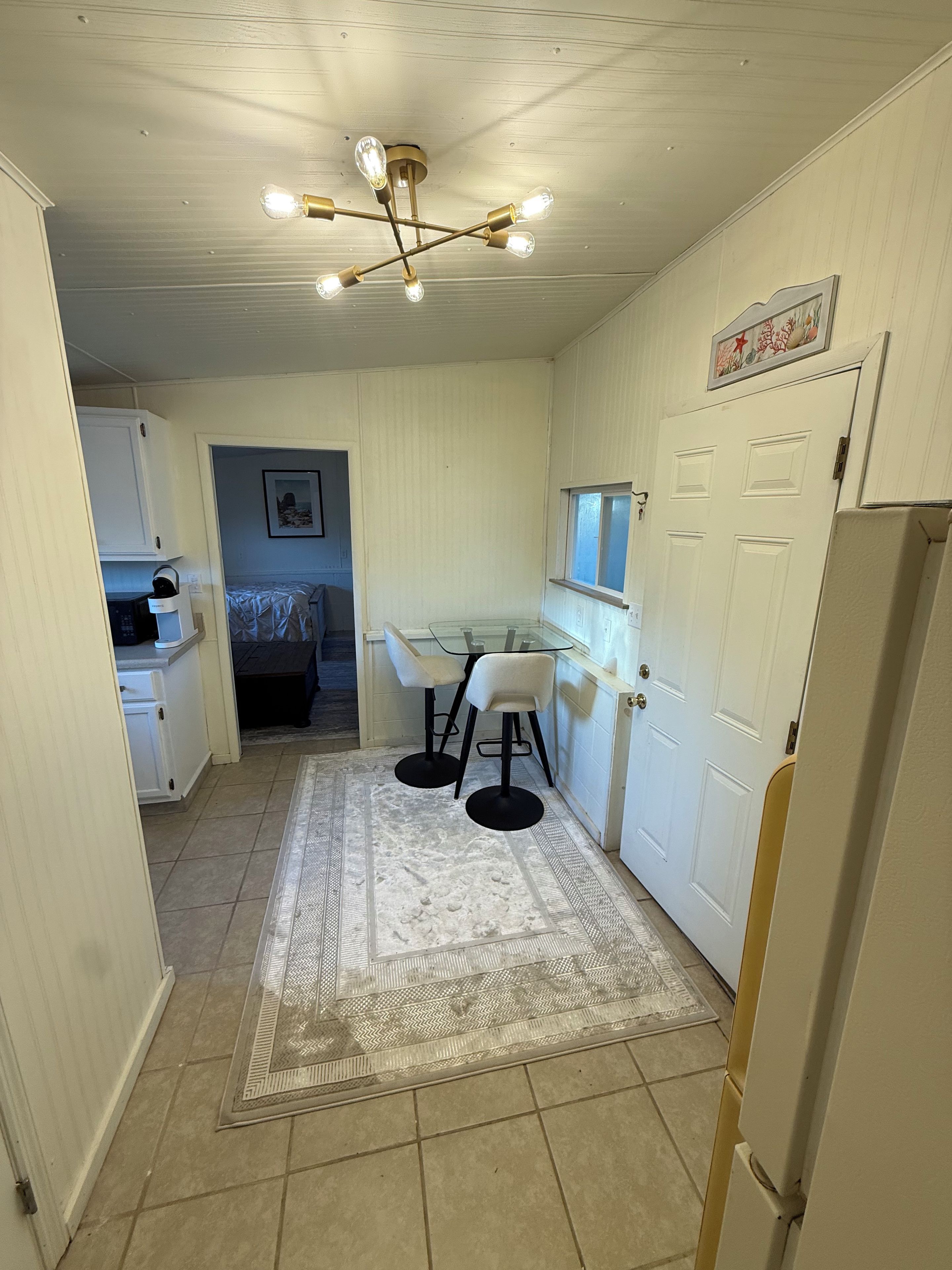 A compact kitchen with a dining area, a refrigerator, and a ceiling light fixture.