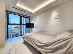 Ein modernes Schlafzimmer mit einem großen Bett, einem Flachbildfernseher und einem Balkon mit einem Stuhl.