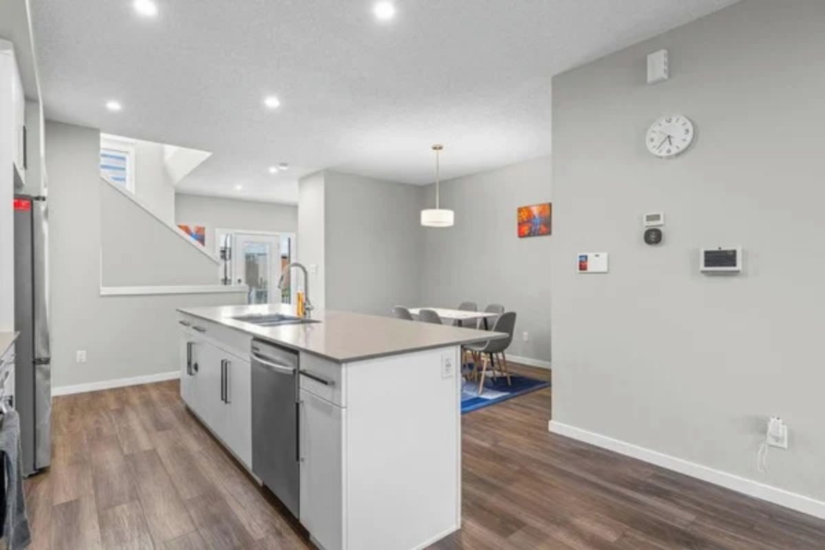 A modern kitchen with a central island, built-in appliances, and a dining area with a table and chairs.
