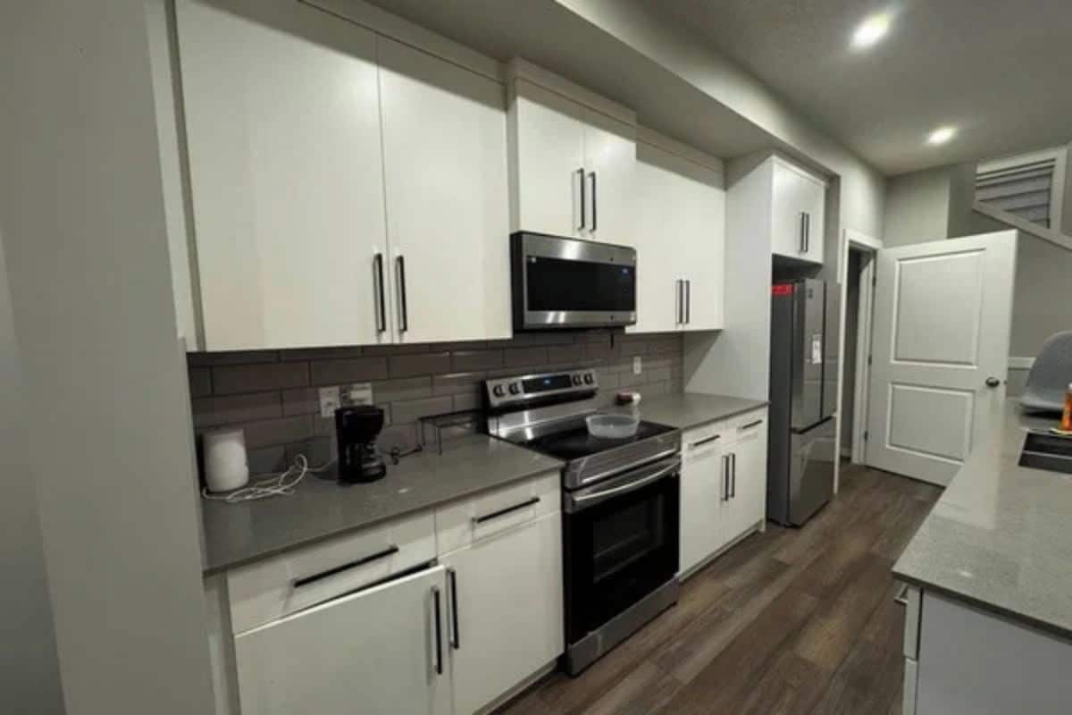 A modern kitchen with white cabinets, stainless steel appliances, and a tiled backsplash.