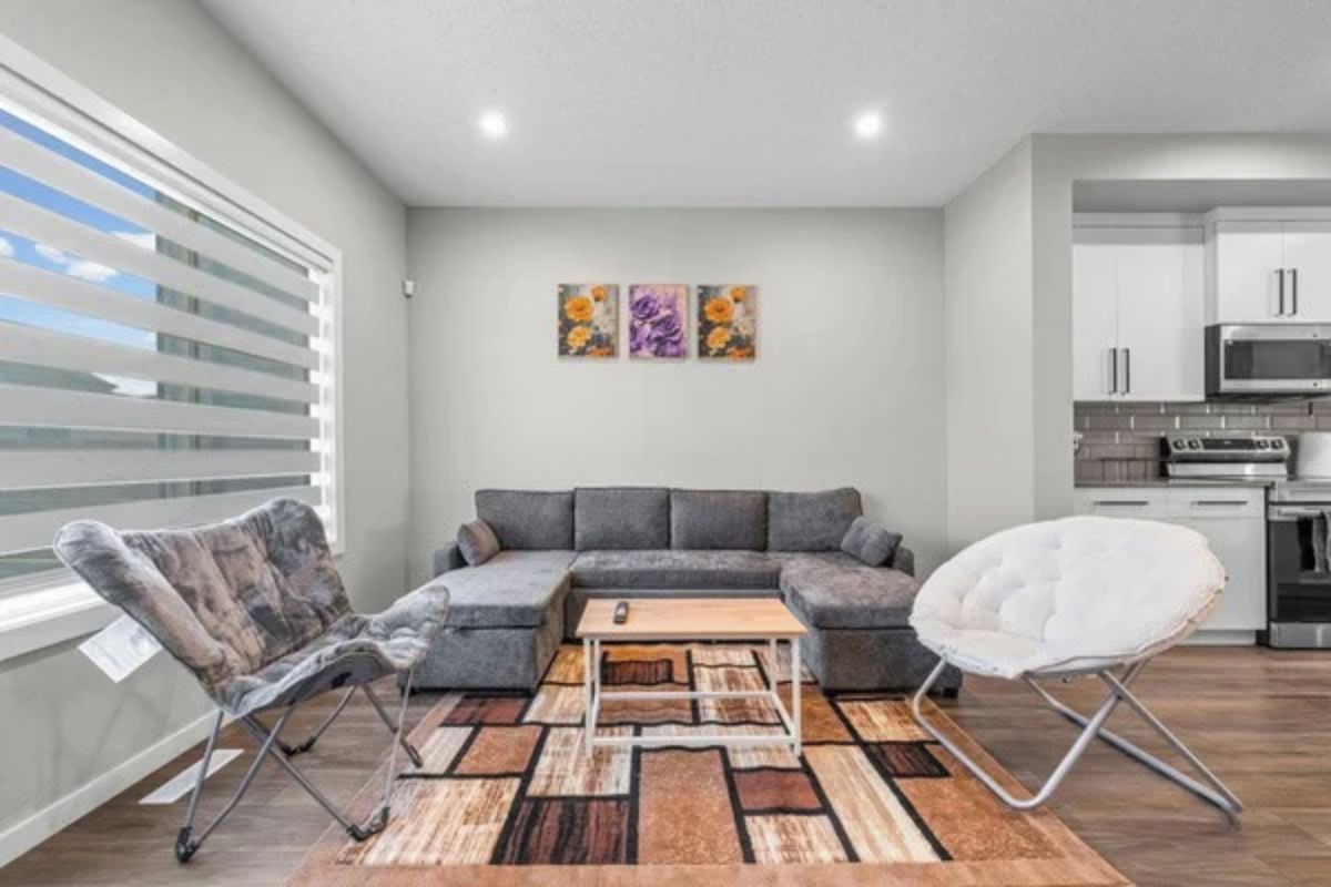 Uma sala de estar moderna com um sofá seccional, uma mesa de centro e um tapete estampado.