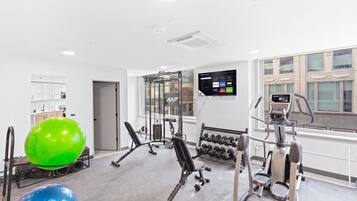 A modern gym with cardio equipment, weight machines, and exercise balls.