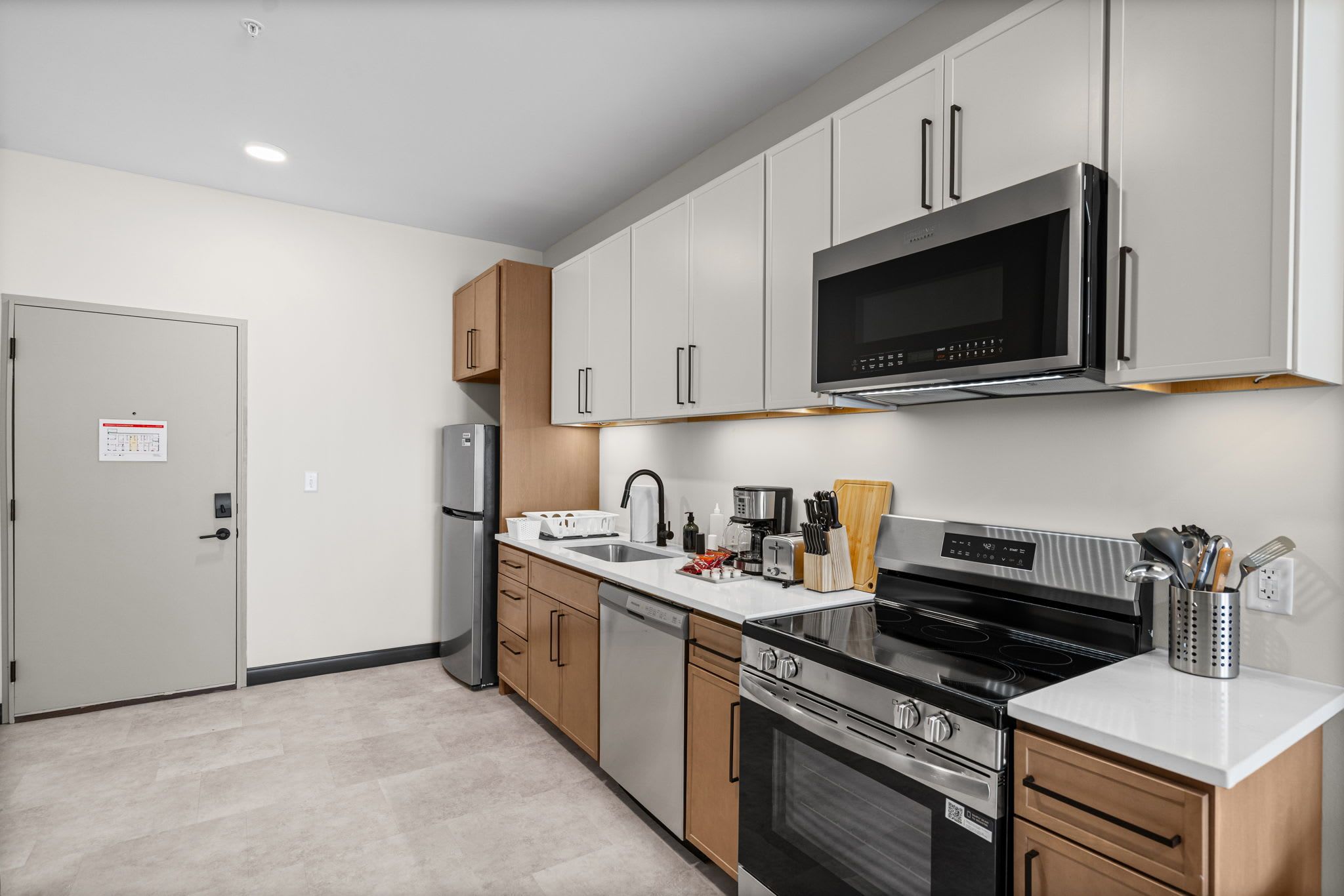 A modern kitchen with stainless steel appliances, wooden cabinets, and a white countertop.