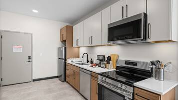 A modern kitchen with stainless steel appliances, wooden cabinets, and a white countertop.