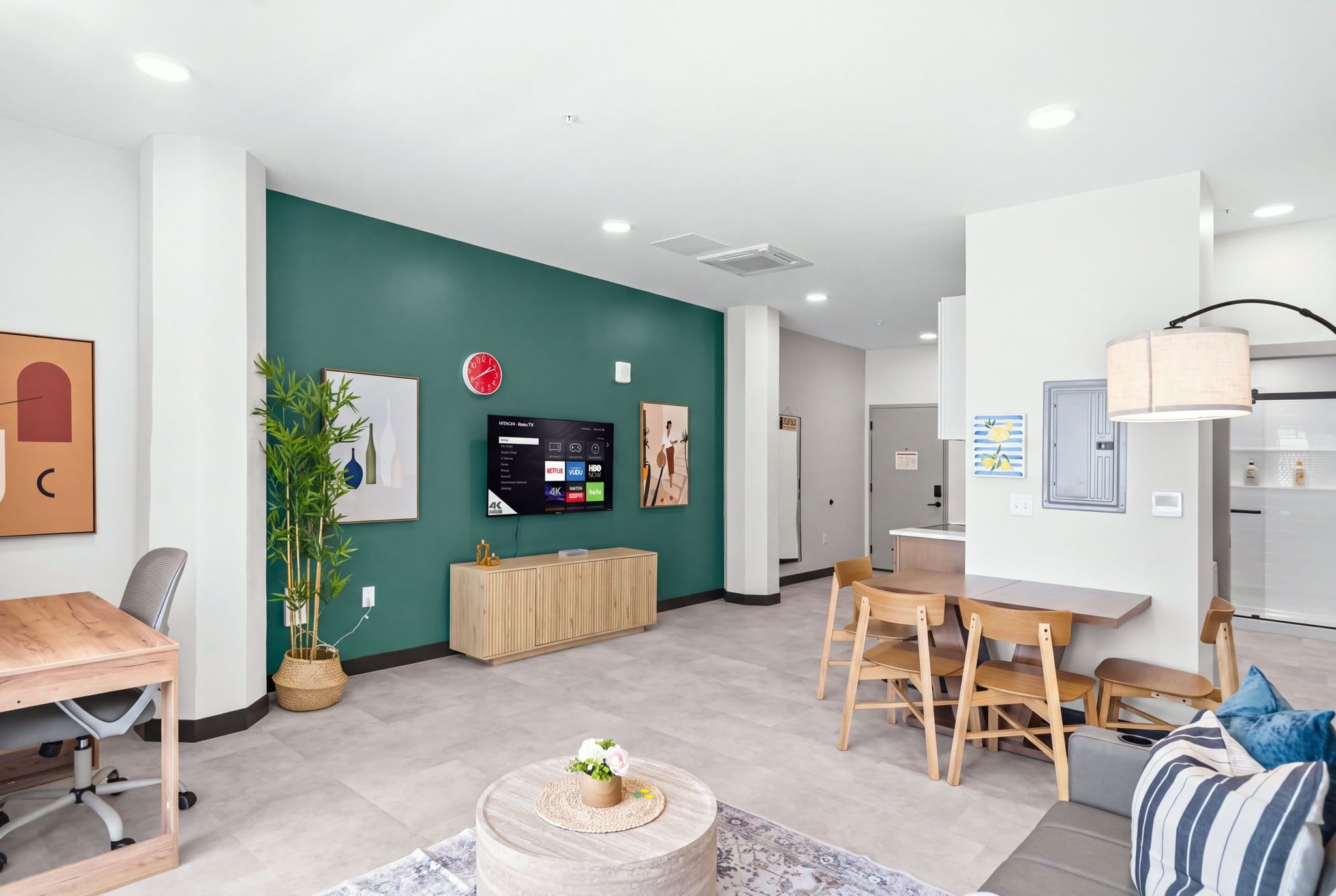 A modern living room with a TV, seating area, and a dining table.
