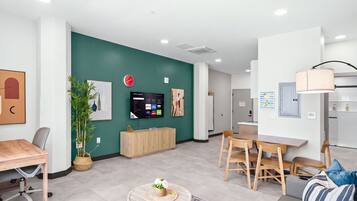 A modern living room with a TV, seating area, and a dining table.