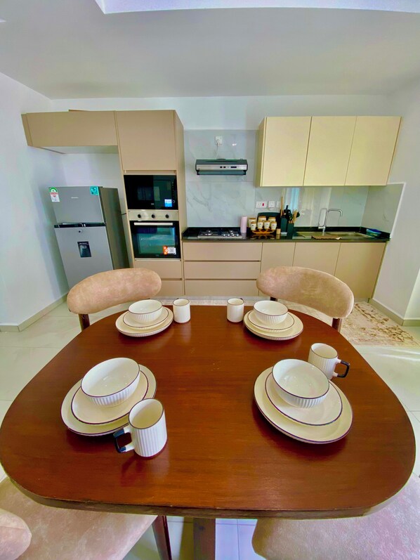 Uma sala de jantar com uma mesa de madeira posta para quatro pessoas, cercada por cadeiras.