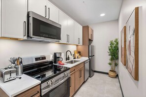 Una cocina moderna con electrodomésticos de acero inoxidable, horno empotrado y pileta.
