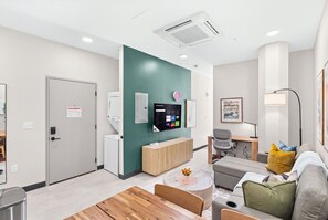 Un área de espera moderna con mostrador de recepción, asientos, un televisor montado y un reloj en la pared.