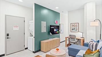 A modern living room with a flat-screen TV, a clock, a desk, and a sofa.
