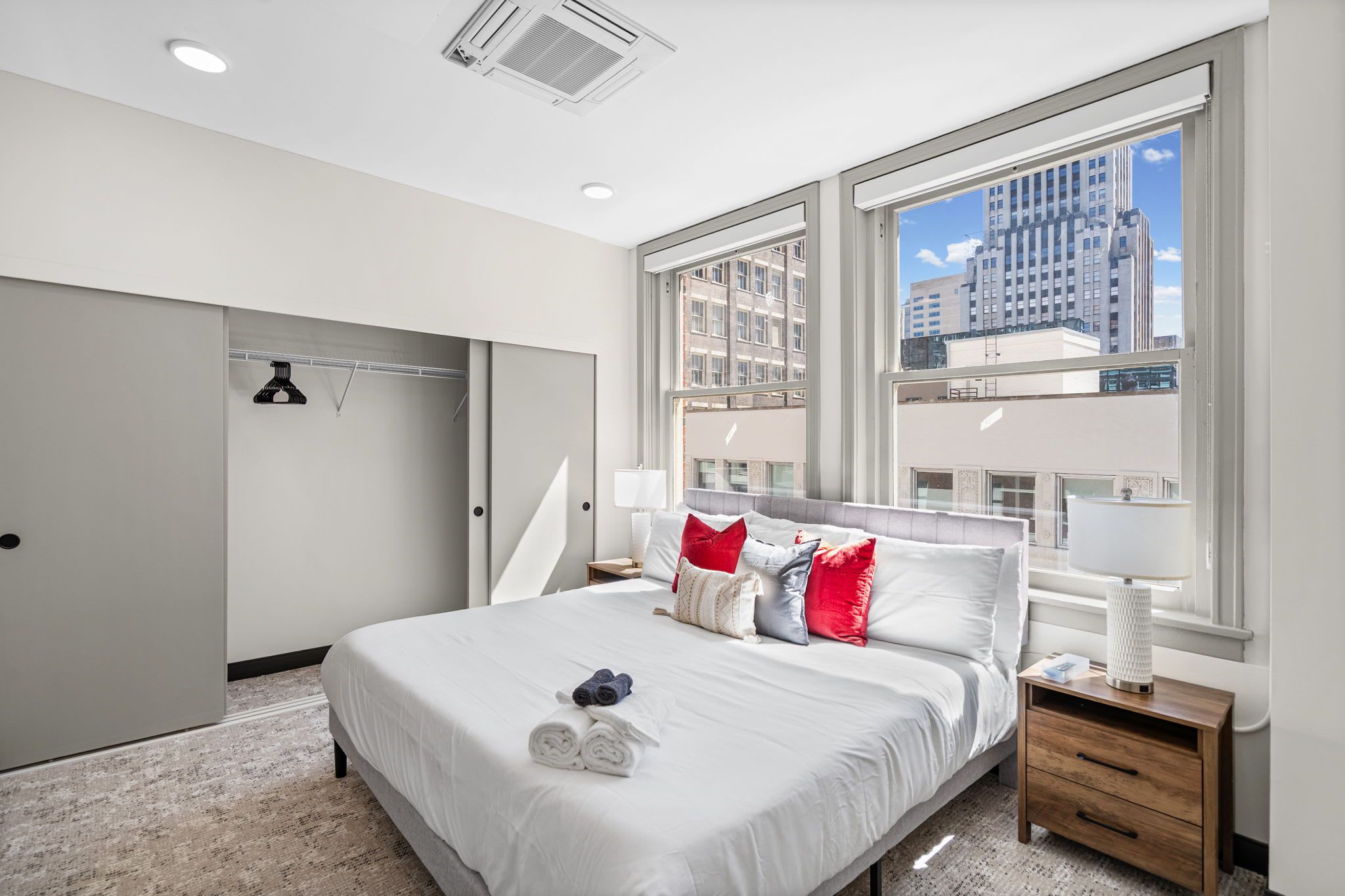 Een moderne slaapkamer met een groot bed, een inloopkast en uitzicht over de stad.