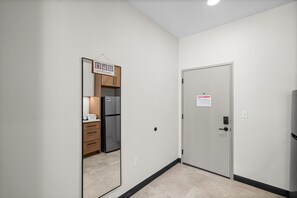 A hallway with a door, a refrigerator, and a welcome sign. - Central Flat: Free Attached Parking | Rooftop |Gym (Kansas City)